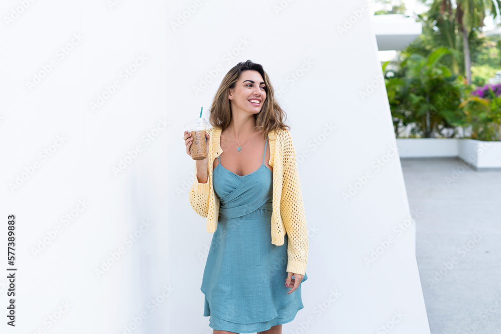 Portrait of beautiful woman in green summer dress on white background natural daylight, holding iced coffee cappuccino happy smiling excited Portrait of beautiful woman in green summer dress on white background natural daylight, holding iced coffee cappuccino happy smiling excited
