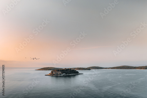 Experience the Beauty of Paklinski Islands at Sunrise with Our Aerial Photography. Our stunning shot captures the breathtaking view of the islands and the sea illuminated by the soft, warm light .