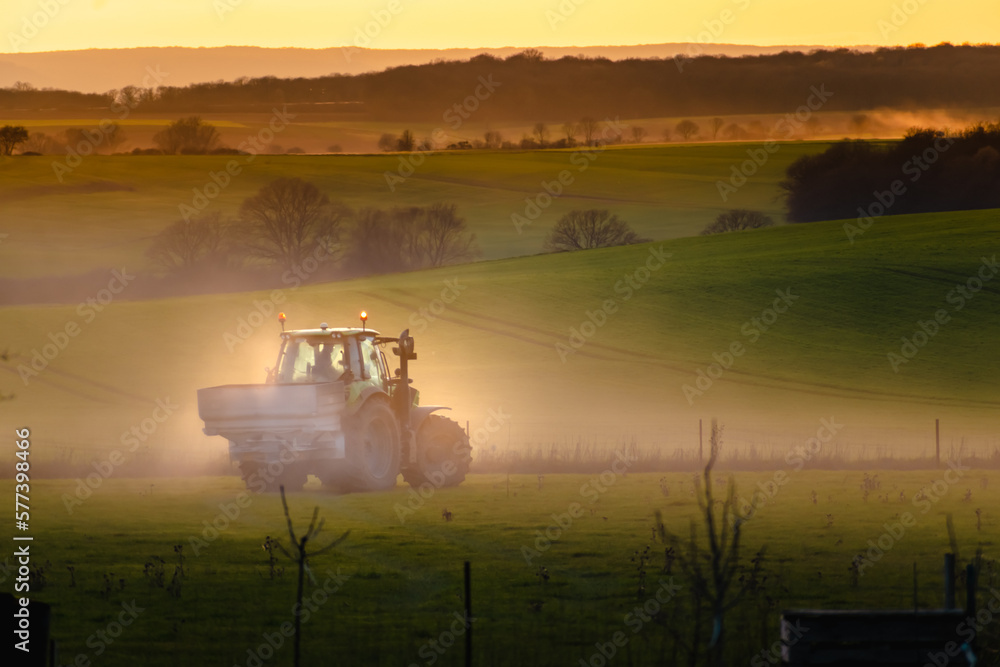 Tractor in farmland working on soil field with sunset, big equipment, countryside scene Tractor in farmland working on soil field with sunset, big equipment, countryside scene