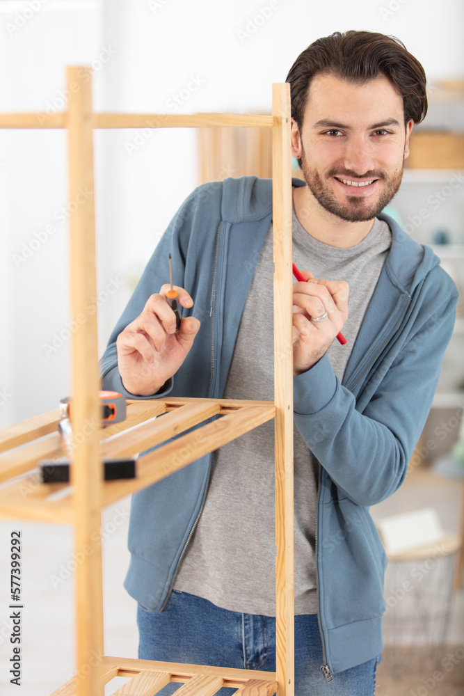 the young man tries himself to mount a new shelf the young man tries himself to mount a new shelf