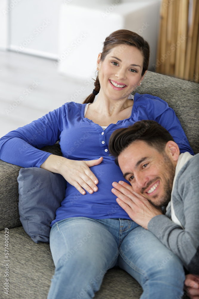 glad future father rests head on abdomen of pregnant wife