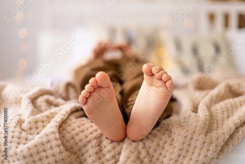 legs in focus, feet of a small child on the bed in beige brown natural tones