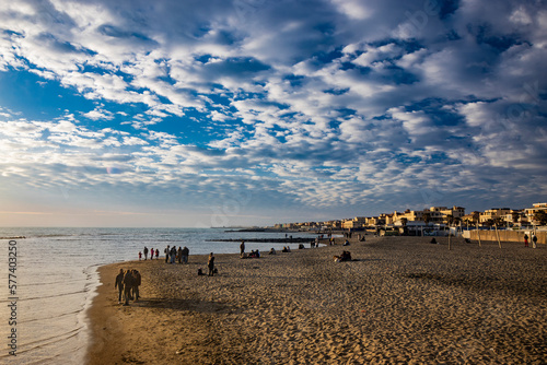 Fototapeta Naklejka Na Ścianę i Meble -  February 12, 2023 - Ostia, Rome, Italy. The sea of Ostia, on the Roman coast, on a winter Sunday. People enjoy the public holiday by walking on the beach in the open air in the evening.