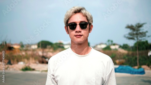 Asian teenager man in sunglasses smiling face at outdoors looking at camera