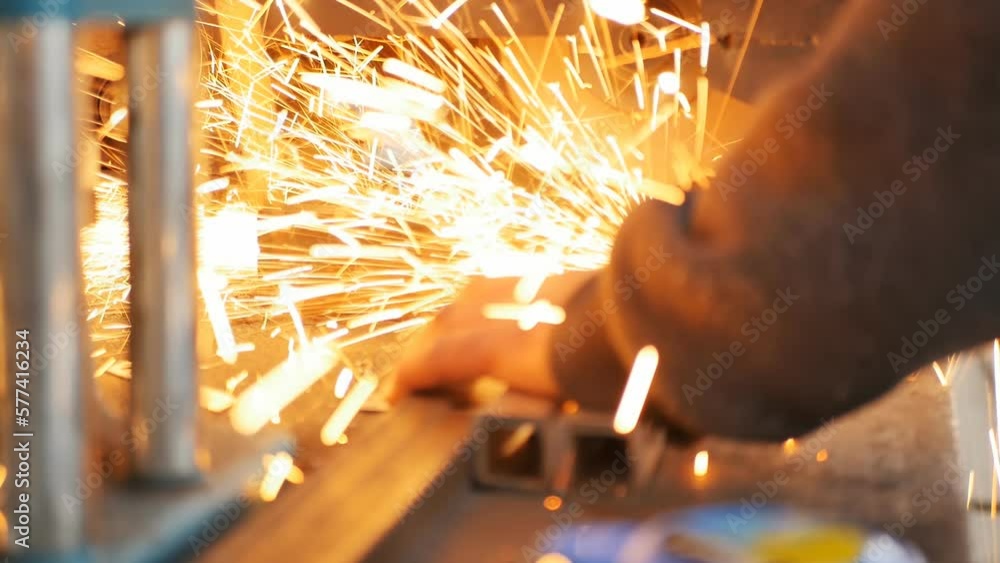 A worker, using an industrial miter saw, cuts iron square