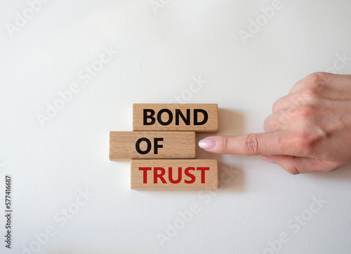 Bond of trust symbol. Wooden blocks with words Bond of trust. Beautiful white background. Businessman hand. Business and Bond of trust concept. Copy space.