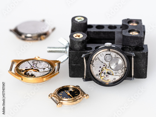 open steel mechanical watch and old watches on white board in watchmaker workshop
