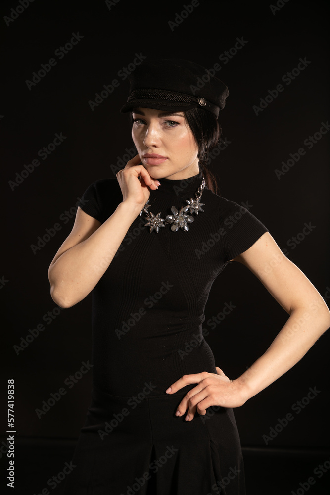 a brunette woman in a hat poses on a black background a brunette woman in a hat poses on a black background