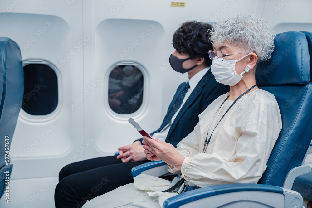 飛行機で旅行をする高齢の女性 飛行機で旅行をする高齢の女性