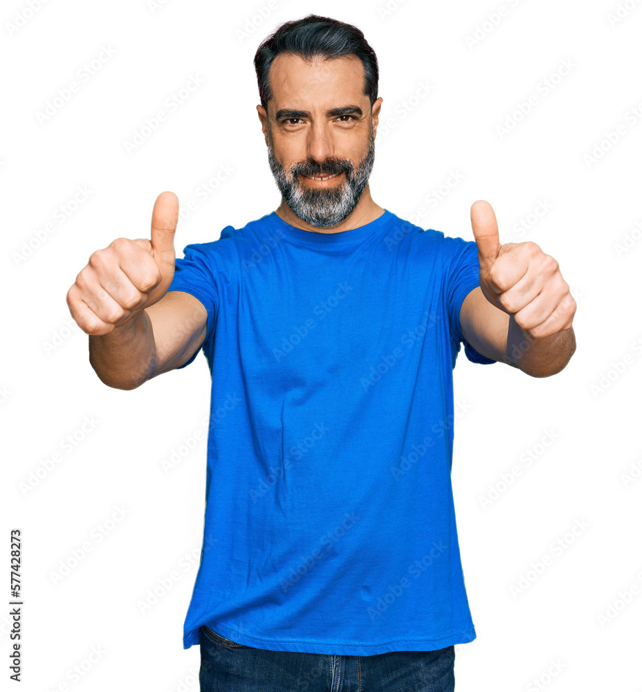 Middle aged man with beard wearing casual blue t shirt approving doing positive gesture with hand, thumbs up smiling and happy for success. winner gesture. Middle aged man with beard wearing casual blue t shirt approving doing positive gesture with hand, thumbs up smiling and happy for success. winner gesture.