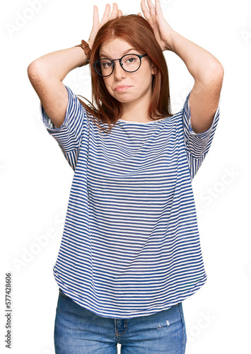 Young read head woman wearing casual clothes and glasses doing bunny ears gesture with hands palms looking cynical and skeptical. easter rabbit concept.