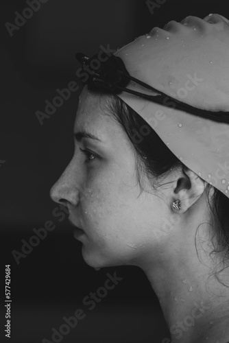 Extreme close-up shot of a Caucasian girl head with a swimming cap and hands putting swimming goggles, preparing for training in the pool. photo