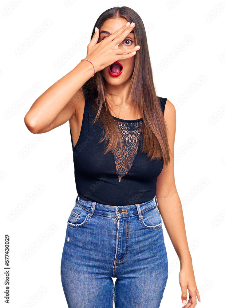 Young hispanic woman wearing casual clothes peeking in shock covering face and eyes with hand, looking through fingers with embarrassed expression. Young hispanic woman wearing casual clothes peeking in shock covering face and eyes with hand, looking through fingers with embarrassed expression.
