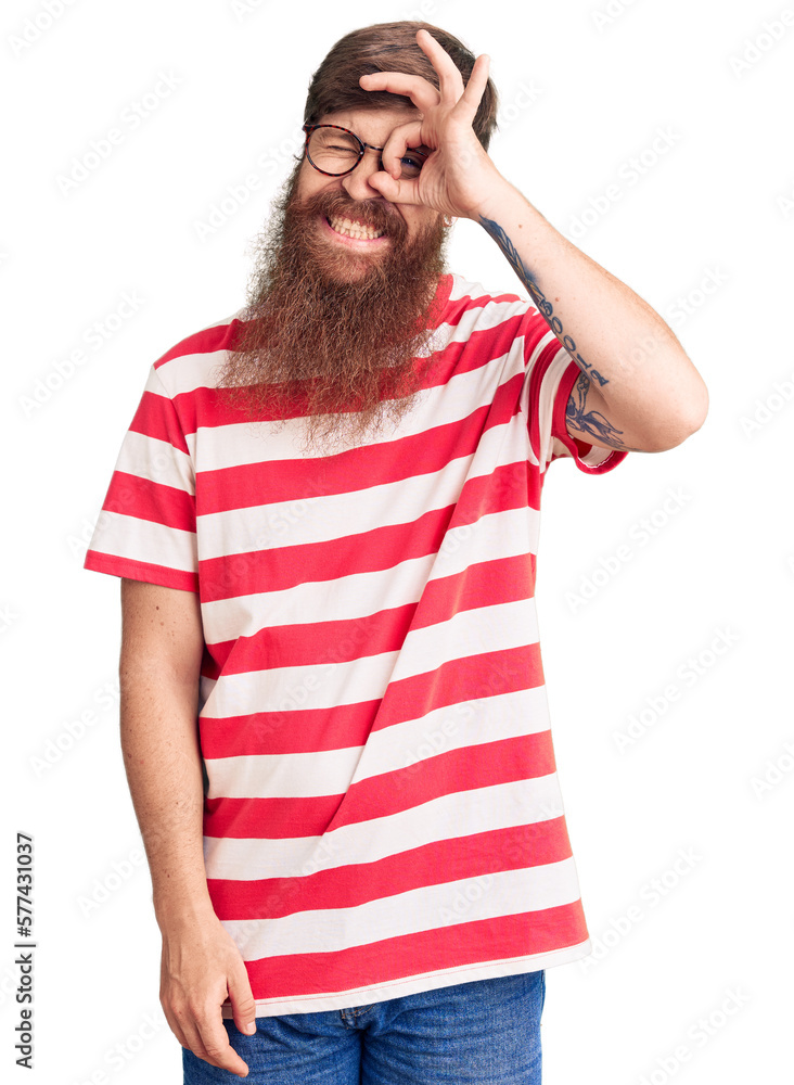 Handsome young red head man with long beard wearing casual clothes doing ok gesture with hand smiling, eye looking through fingers with happy face. Handsome young red head man with long beard wearing casual clothes doing ok gesture with hand smiling, eye looking through fingers with happy face.