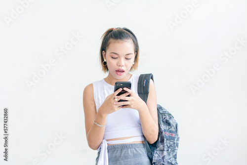 A short haired student wearing a white sleeveless top and printed skirt using her phone isolated on a white background