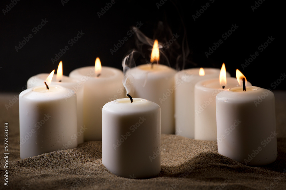 bullying concept, composed by group of lit candles, on sand with black night background bullying concept, composed by group of lit candles, on sand with black night background