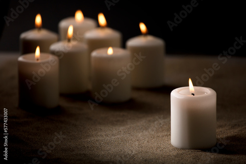 bullying concept, composed by group of lit candles, on sand with black night background