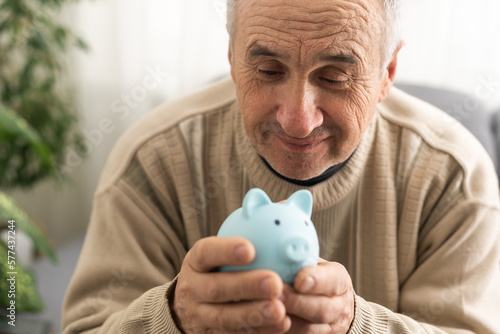 Fotografija Senior man holding piggy bank