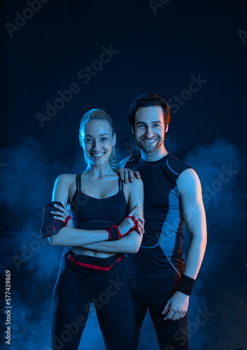 Fototapeta Naklejka Na Ścianę i Meble -  Download photo for advertising a fitness club in social networks. Fitness Influencers. Fitness couple at home. Cover for sport motivation music. Fit man and woman at the gym on black background.