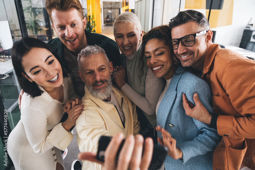 Happy multiethnic colleagues taking picture on smartphone in office Happy multiethnic colleagues taking picture on smartphone in office