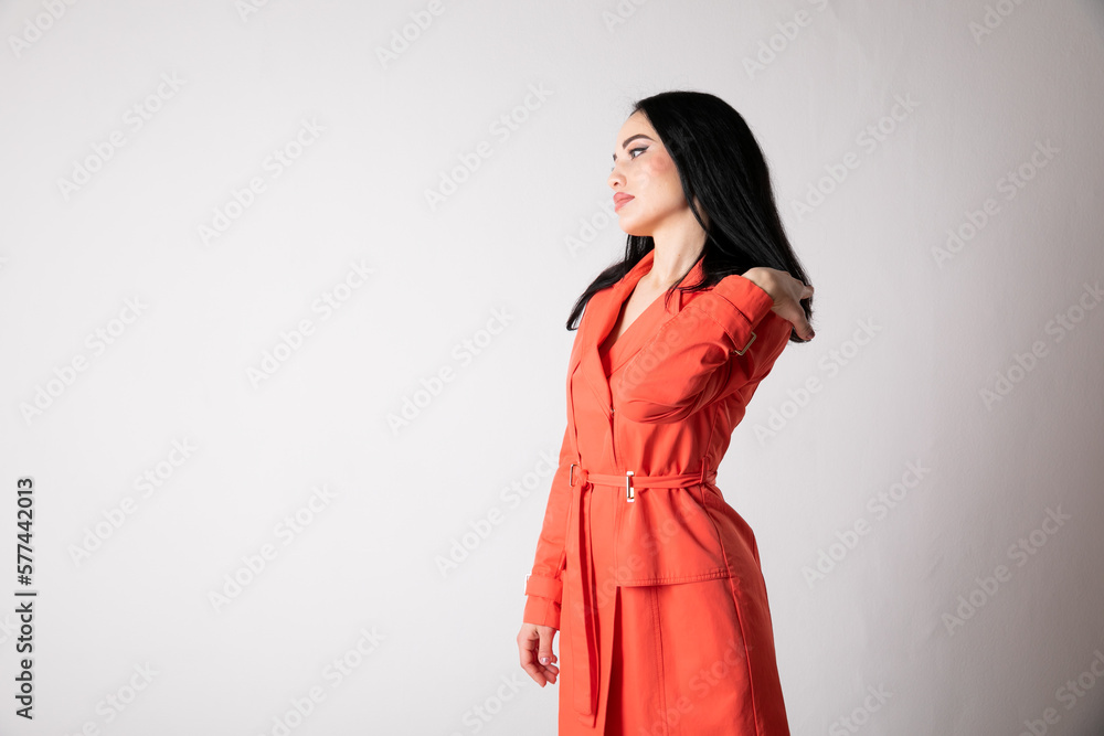 a woman in an orange dress against a light wall a woman in an orange dress against a light wall