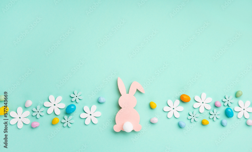 Pink Bunny, Easter Eggs with Sweets and Spring Flowers on Blue Mint Background