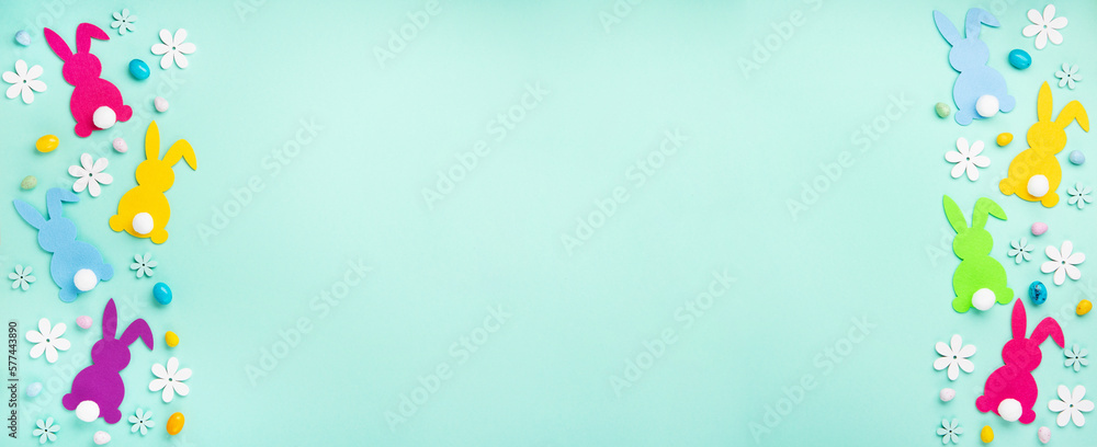 Colorful Bunnies, Easter Eggs with Sweets and Spring Flowers on Blue Background Colorful Bunnies, Easter Eggs with Sweets and Spring Flowers on Blue Background