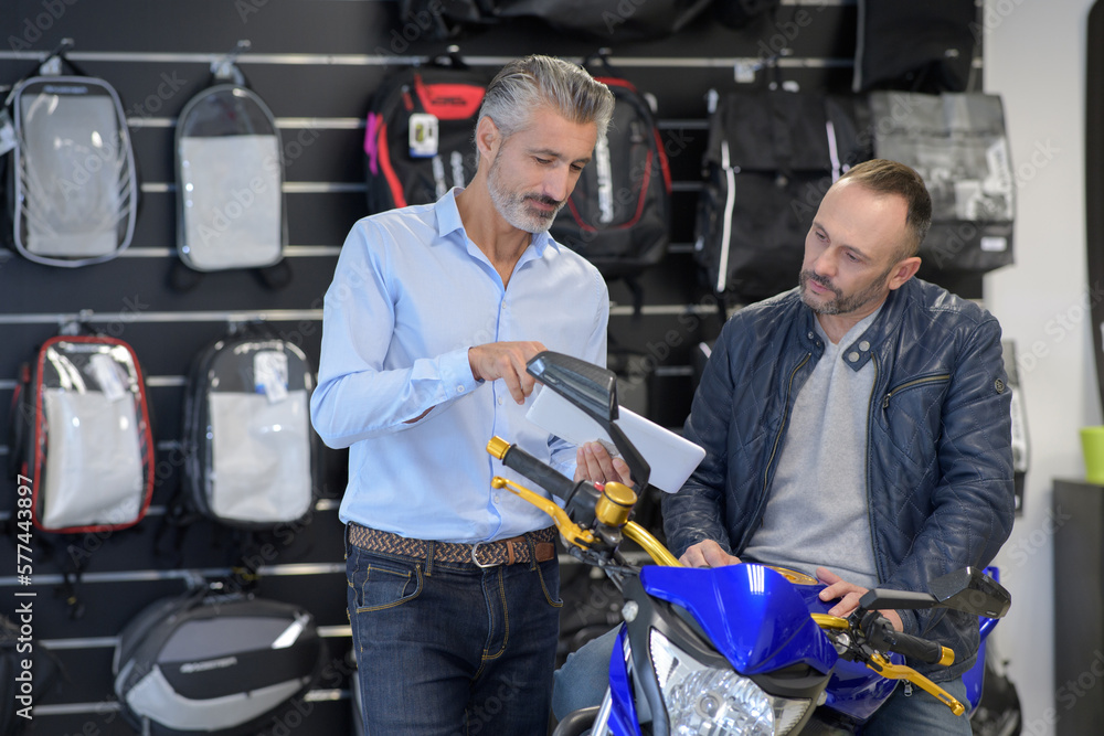 Fototapeta premium man motorcyclist chooses motorcycle accessories in store