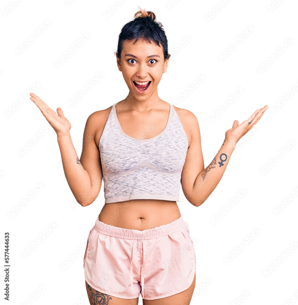 Young woman wearing sportswear celebrating victory with happy smile and winner expression with raised hands Young woman wearing sportswear celebrating victory with happy smile and winner expression with raised hands