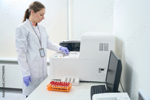 Hematologist laboratory assistant stands near an immunochemiluminescent analyzer