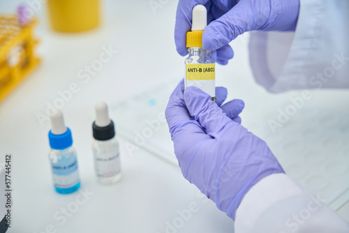Fotografia Hematologist holdsa reagent for determining blood group in his hands