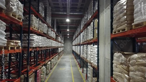 4K Aerial view of chemical warehouse. Wide angle shooting of warehouse and shelves. Symmetrical view of placed up palleted goods. Forest of shelves. Stock video.  