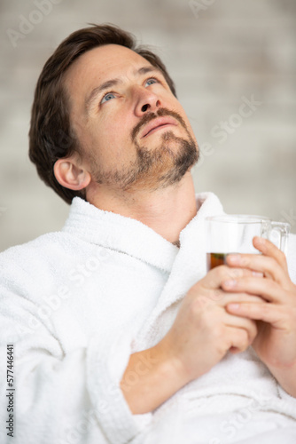 male in bathrobe relaxing while drinking tea