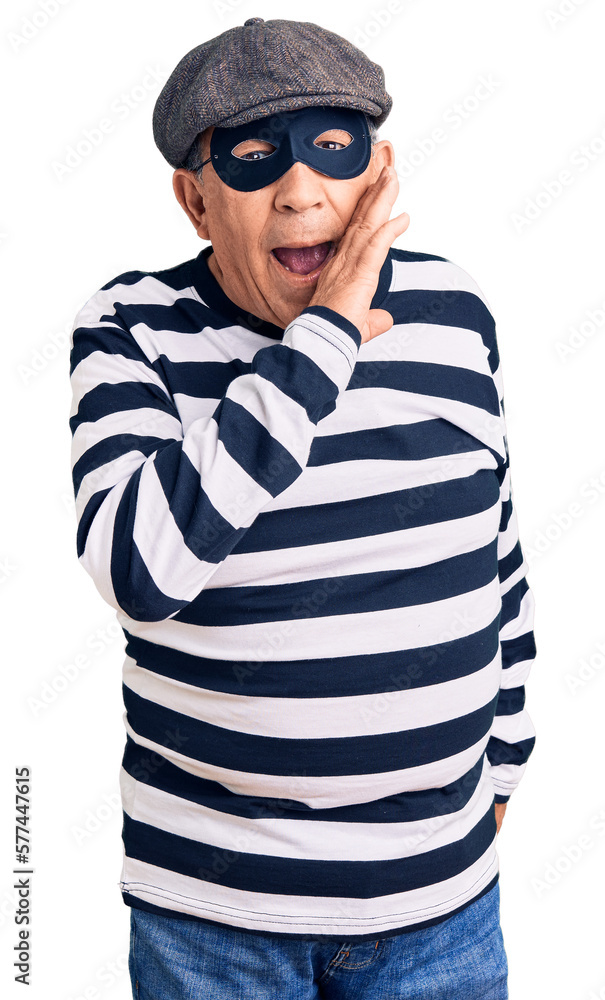 Senior handsome man wearing burglar mask and t-shirt hand on mouth telling secret rumor, whispering malicious talk conversation Senior handsome man wearing burglar mask and t-shirt hand on mouth telling secret rumor, whispering malicious talk conversation