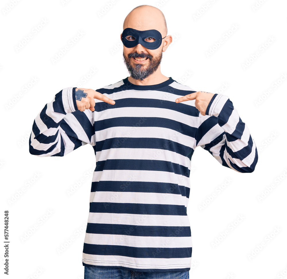 Young handsome man wearing burglar mask looking confident with smile on face, pointing oneself with fingers proud and happy. Young handsome man wearing burglar mask looking confident with smile on face, pointing oneself with fingers proud and happy.