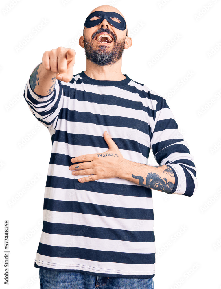 Young handsome man wearing burglar mask laughing at you, pointing finger to the camera with hand over body, shame expression Young handsome man wearing burglar mask laughing at you, pointing finger to the camera with hand over body, shame expression