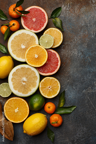 Set of various fresh citrus fruits with leaves and wooden juicer on dark concrete background. Healthy food backround. Flat composition with copy space. Top view © Zygonema
