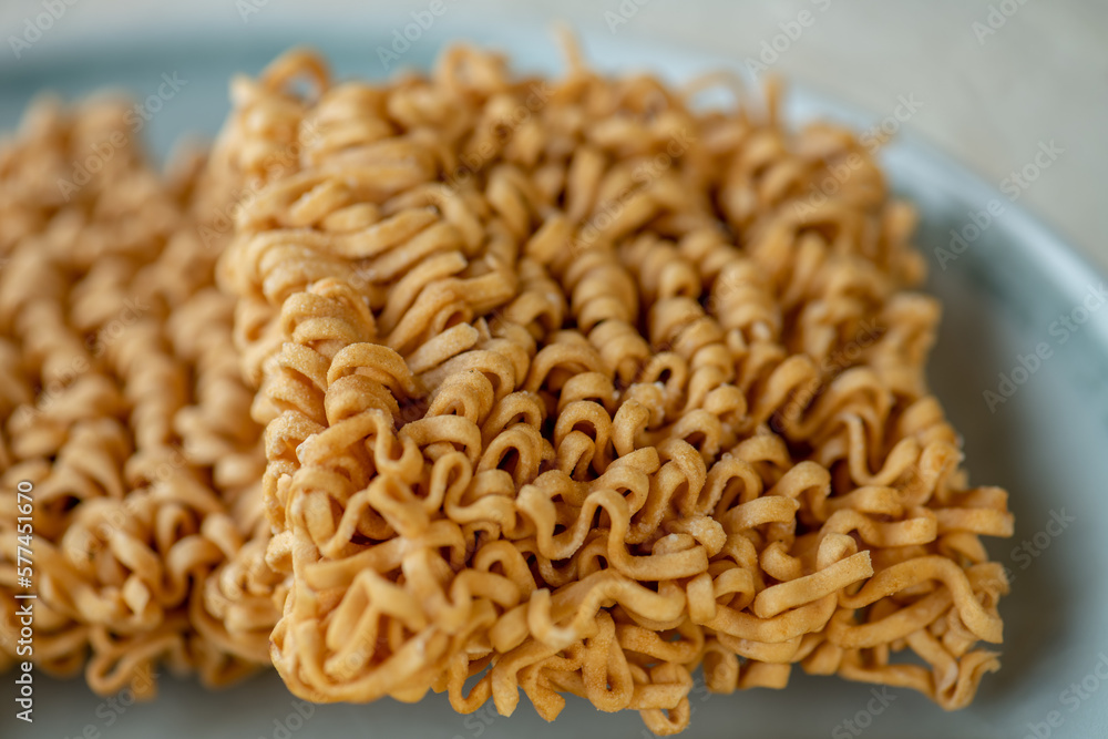 dried Instant noodles on white mulberry paper background. Instant noodles and pasta are wheat flour products call junk convenience food. Chinese and Japanese oriental noodle. dried Instant noodles on white mulberry paper background. Instant noodles and pasta are wheat flour products call junk convenience food. Chinese and Japanese oriental noodle.