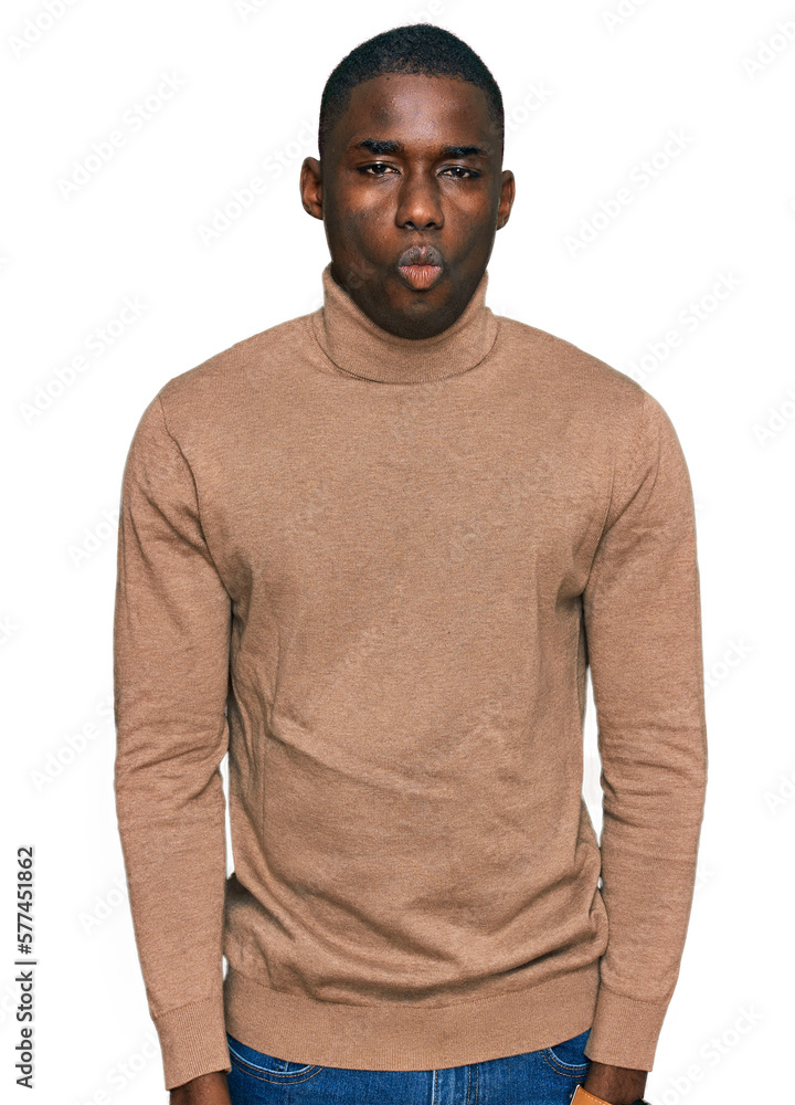 Young african american man wearing casual winter sweater making fish face with lips, crazy and comical gesture. funny expression. Young african american man wearing casual winter sweater making fish face with lips, crazy and comical gesture. funny expression.