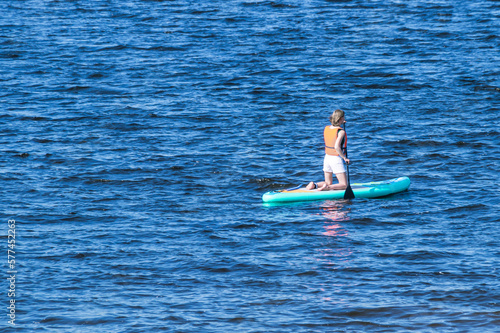 Active recreation on the board on the big river. Tourism on sap boards. Outdoor water sports. Surfers, standing on a board, ride the waves. SUP surfing training. View of the city embankment