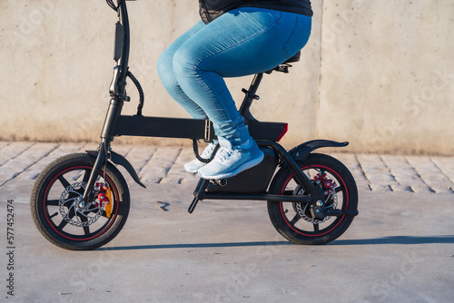 40 year old woman riding her electric scooter through the streets of the city (Concept of electric mobility)