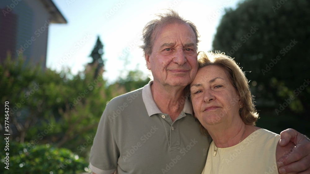 Portrait of a married senior couple standing outside. Older husband with arm around wife. Two elder people close up faces together. Love concept Portrait of a married senior couple standing outside. Older husband with arm around wife. Two elder people close up faces together. Love concept