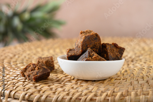 Kithul jaggery and treacle natural sweetener in white bowl on traditional wicker tray. Close up. Alternative sugar. low GI food. Superfood. photo