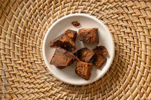 Kithul jaggery and treacle natural sweetener of palm in white bowl on traditional wicker tray. View from above. Alternative sugar. low GI food. Superfood. photo