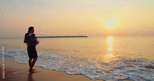 Happy Asian family father carrying embracing baby infant standing relaxing at tropical sandy Beach during Sunset shining sun with waves  Relationship  love  travel  Parenthood  vacation  summertime