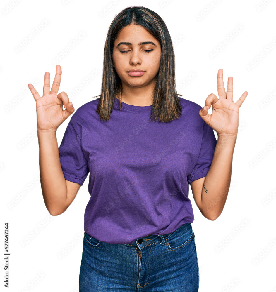 Young hispanic girl wearing casual purple t shirt relax and smiling with eyes closed doing meditation gesture with fingers. yoga concept. Young hispanic girl wearing casual purple t shirt relax and smiling with eyes closed doing meditation gesture with fingers. yoga concept.
