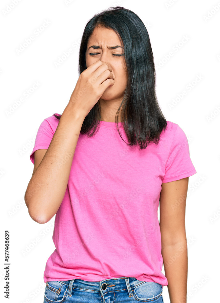 Beautiful asian young woman wearing casual pink t shirt smelling something stinky and disgusting, intolerable smell, holding breath with fingers on nose. bad smell Beautiful asian young woman wearing casual pink t shirt smelling something stinky and disgusting, intolerable smell, holding breath with fingers on nose. bad smell
