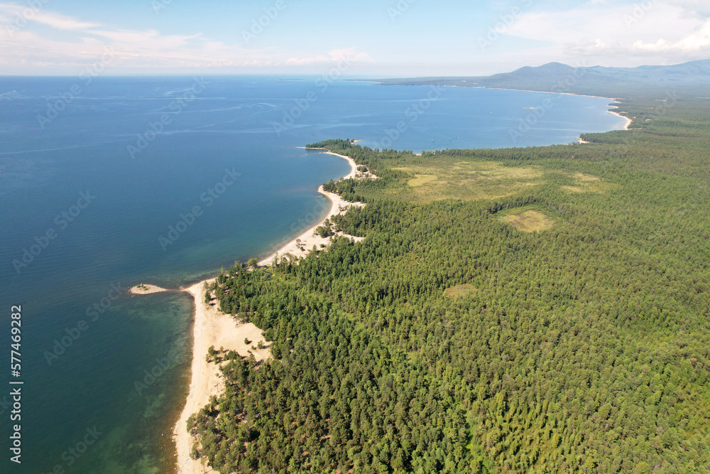 Beautiful summer seascape from the air. Sandy beach, rugged coastline, coniferous forest.