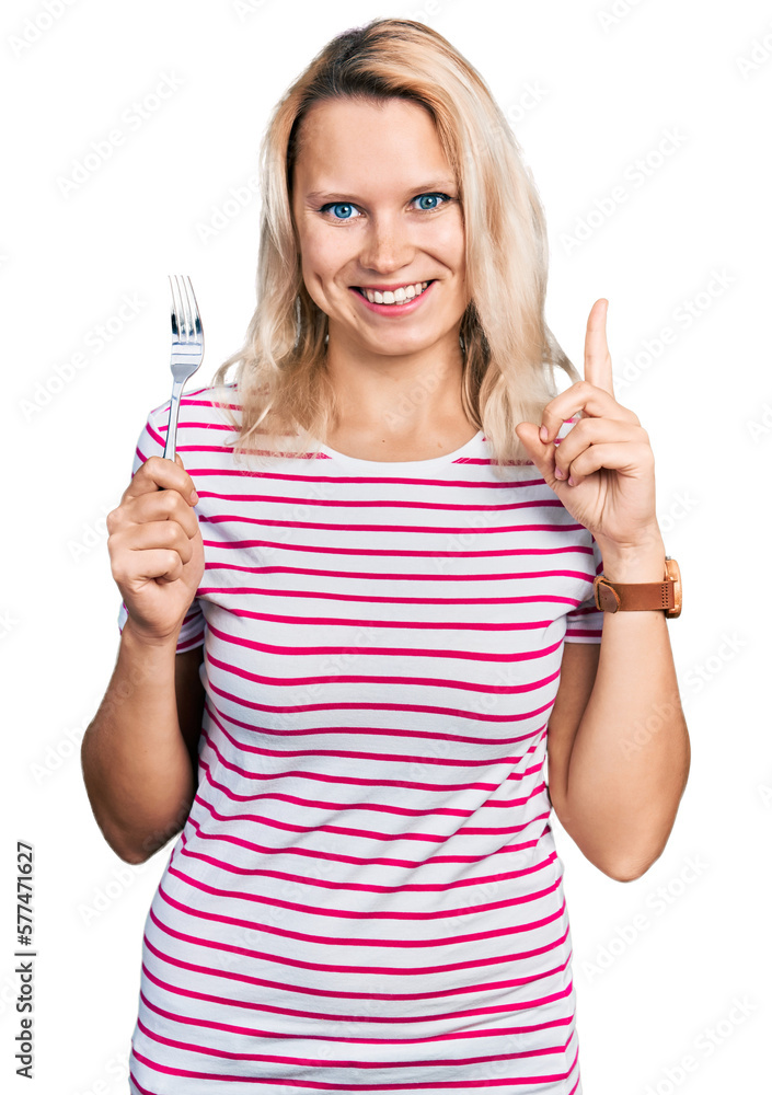 Young caucasian woman holding one silver fork smiling with an idea or question pointing finger with happy face, number one Young caucasian woman holding one silver fork smiling with an idea or question pointing finger with happy face, number one