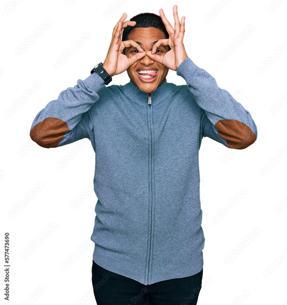 Fototapeta premium Young handsome hispanic man wearing casual sweatshirt doing ok gesture like binoculars sticking tongue out, eyes looking through fingers. crazy expression.